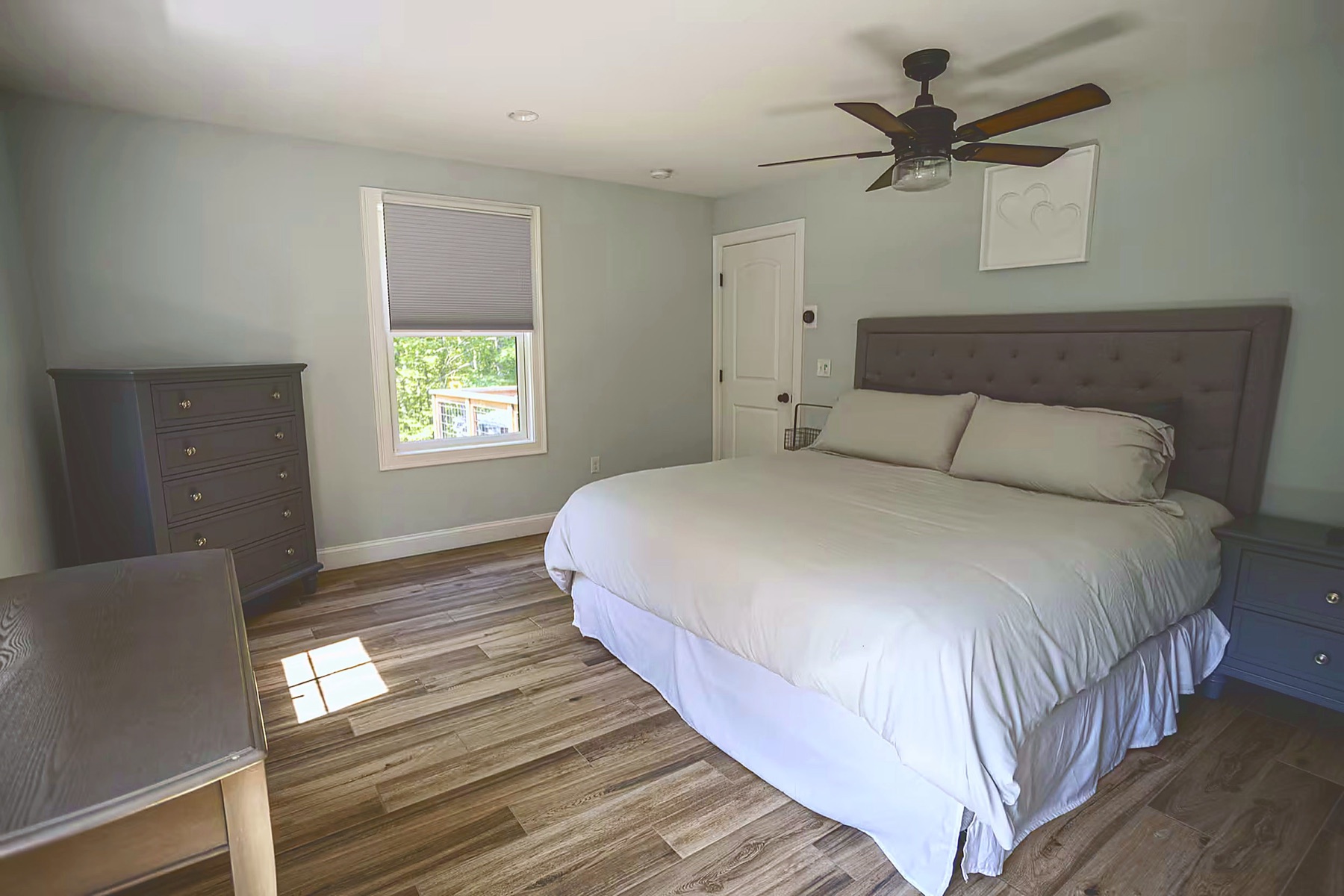 Bedroom with a queen bed, ceiling fan, dresser, and a window onto the upper deck